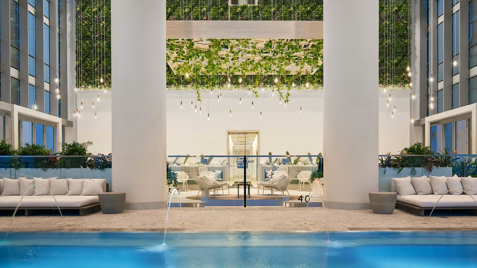 Luxurious indoor pool and lounge area at Sentral Michigan Avenue in Chicago, featuring elegant daybeds and lush vertical gardens