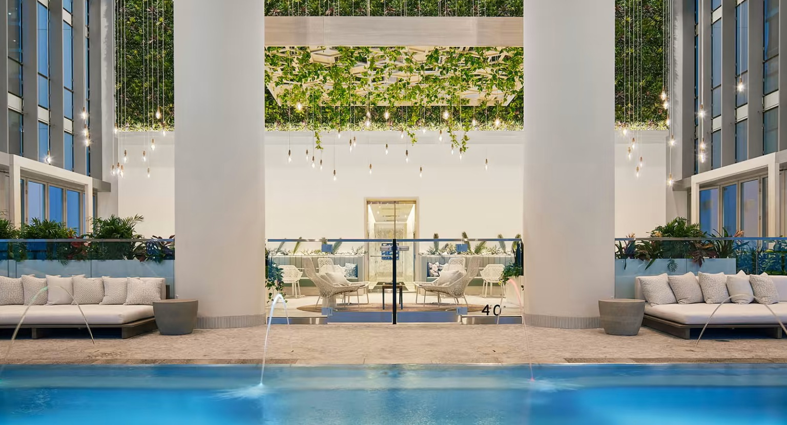 Luxurious indoor pool and lounge area at Sentral Michigan Avenue in Chicago, featuring elegant daybeds and lush vertical gardens