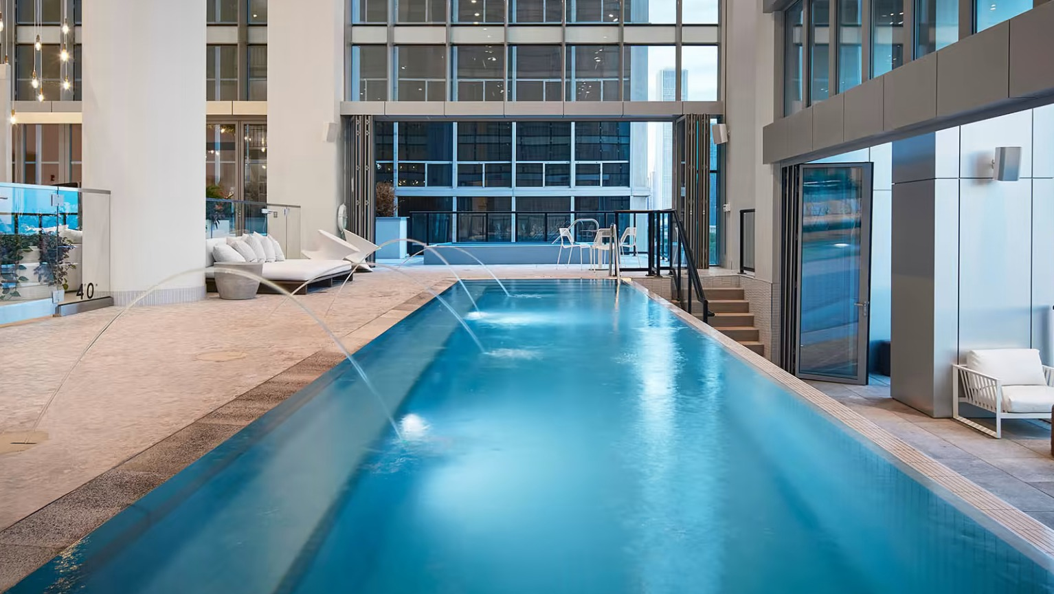Sleek infinity pool at Sentral Michigan Avenue in Chicago, featuring water features, lounge areas, and expansive city views