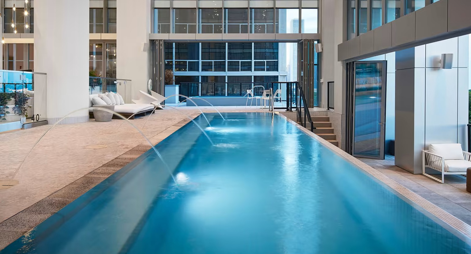 Sleek infinity pool at Sentral Michigan Avenue in Chicago, featuring water features, lounge areas, and expansive city views