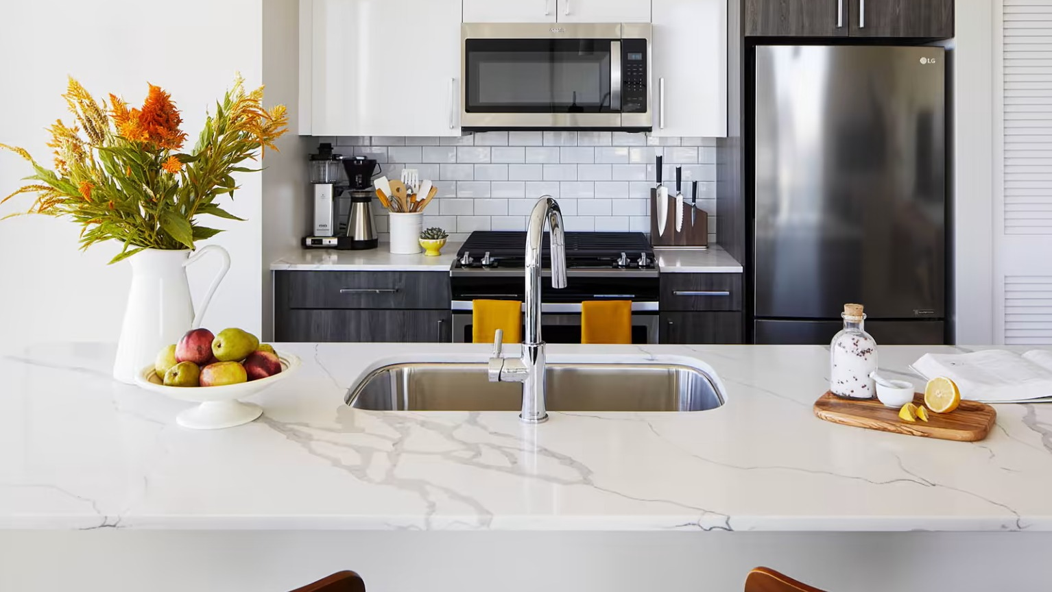 Gourmet apartment kitchen at Sentral Michigan Avenue in Chicago, featuring stainless steel appliances, a white subway tile backsplash, and a spacious island