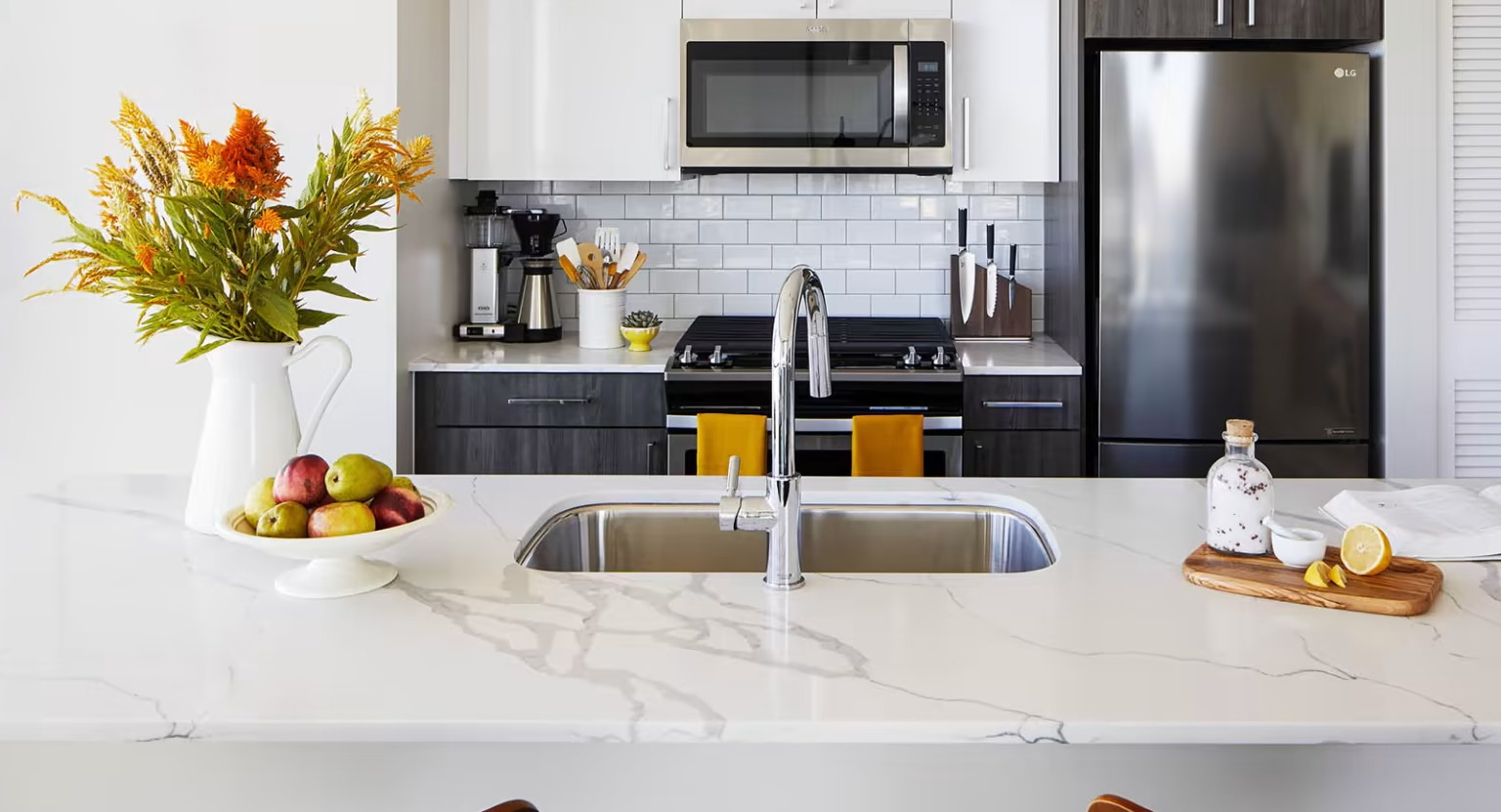 Gourmet apartment kitchen at Sentral Michigan Avenue in Chicago, featuring stainless steel appliances, a white subway tile backsplash, and a spacious island