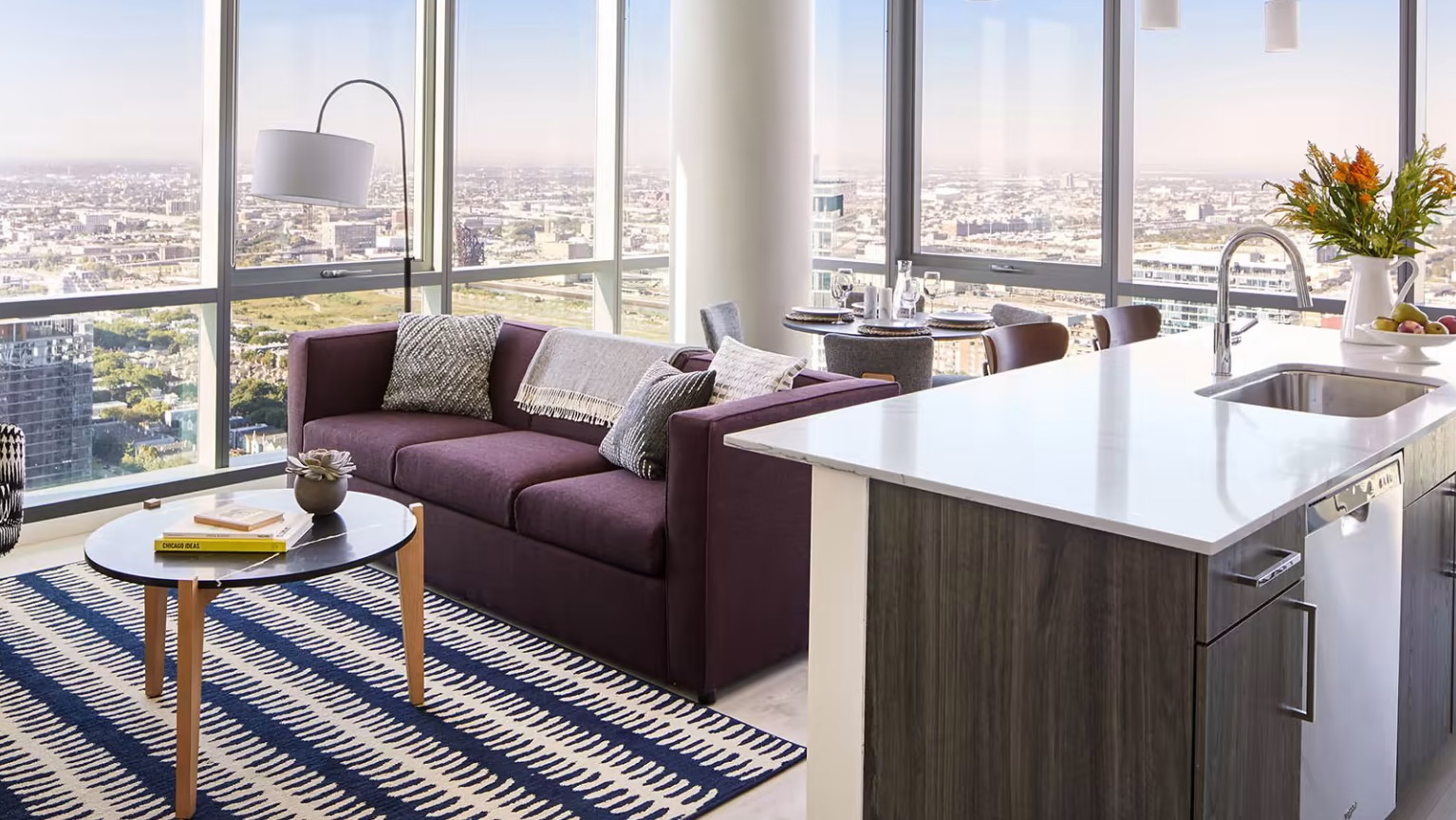 Modern apartment living room at Sentral Michigan Avenue in Chicago, featuring a comfortable sofa, stylish rug, and expansive city views