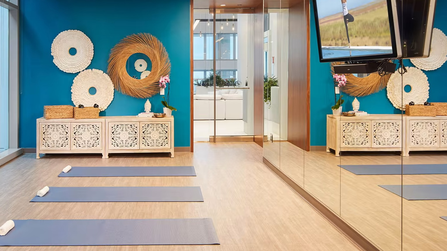 Serene yoga and meditation studio at Sentral Michigan Avenue in Chicago, featuring vibrant blue walls, yoga mats, and mirrors