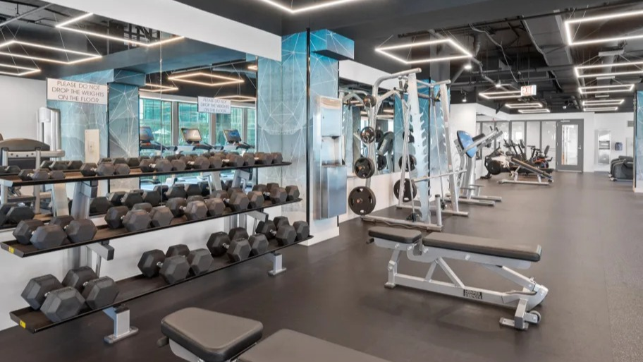 Full fitness center at Shoreham and Tides apartments in Chicago featuring free weights, benches, and modern training equipment for residents