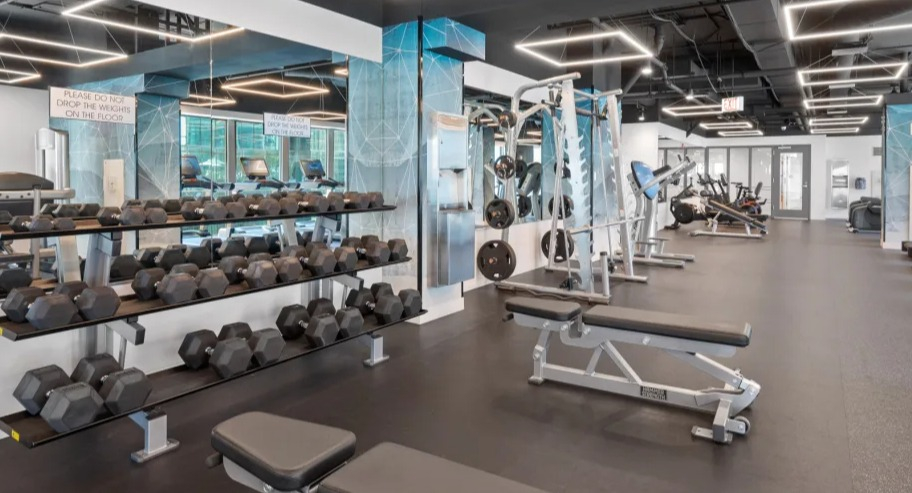 Full fitness center at Shoreham and Tides apartments in Chicago featuring free weights, benches, and modern training equipment for residents