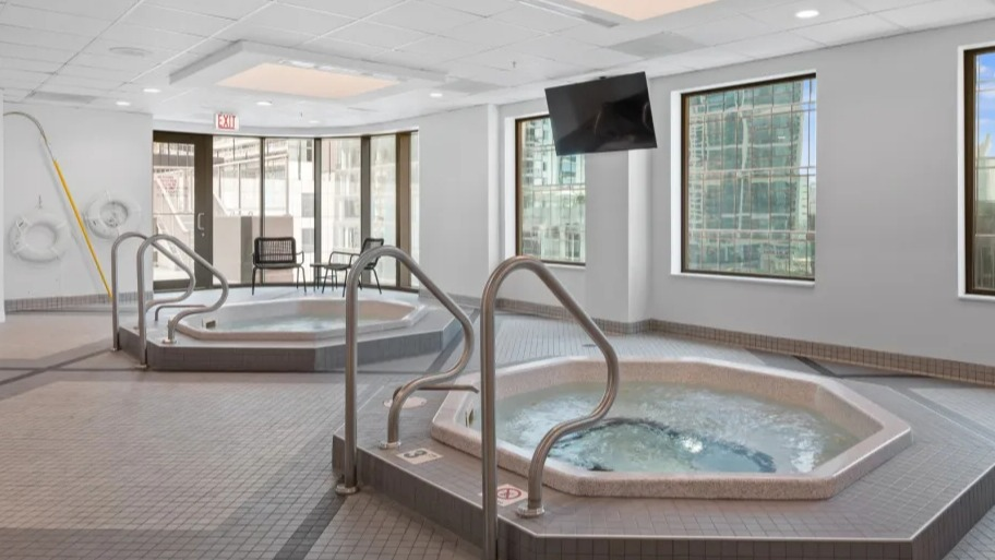 Indoor spa area at Shoreham and Tides apartments in Chicago with two bubbling hot tubs, tiled floors, and large windows for natural light