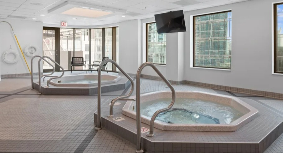 Indoor spa area at Shoreham and Tides apartments in Chicago with two bubbling hot tubs, tiled floors, and large windows for natural light