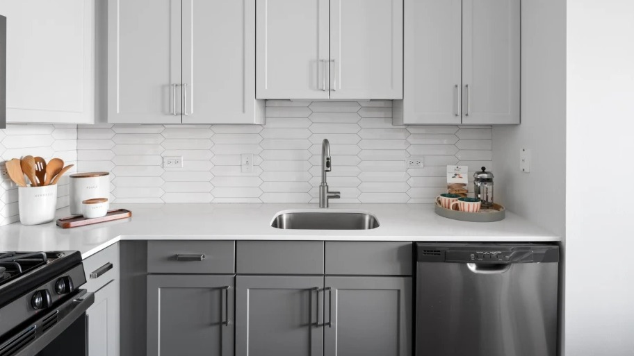 Bright kitchen at Shoreham and Tides apartments in Chicago featuring white tile backsplash, sleek faucet, and gray cabinetry with ample storage