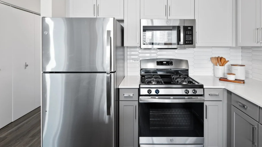 Modern kitchen at Shoreham and Tides apartments in Chicago with stainless steel refrigerator, gas range, and microwave framed by shaker cabinets
