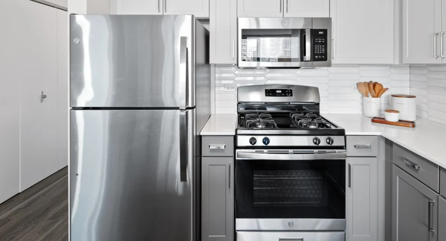 Modern kitchen at Shoreham and Tides apartments in Chicago with stainless steel refrigerator, gas range, and microwave framed by shaker cabinets