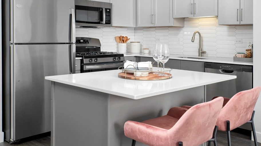 Contemporary kitchen at Shoreham and Tides apartments in Chicago with quartz island, pink barstools, and stainless appliances