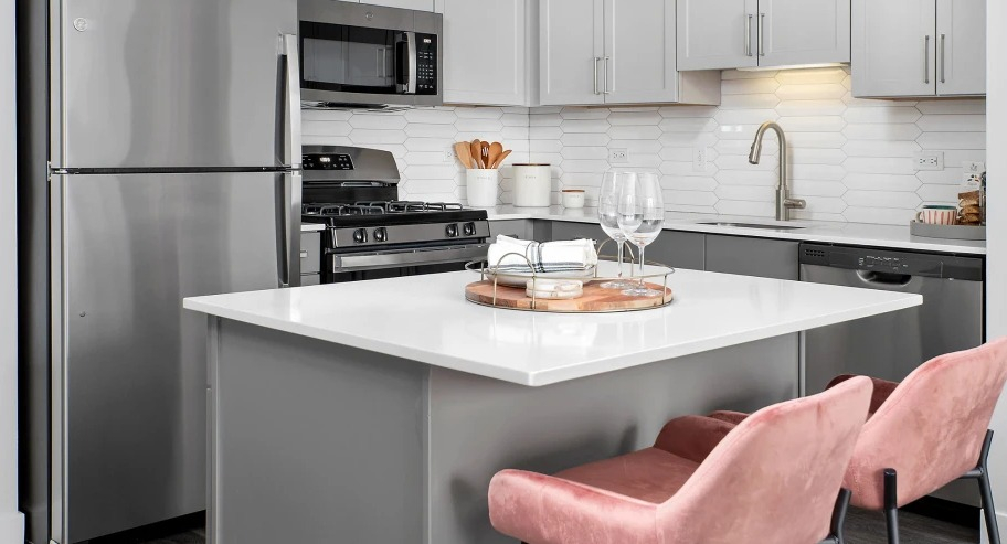 Contemporary kitchen at Shoreham and Tides apartments in Chicago with quartz island, pink barstools, and stainless appliances