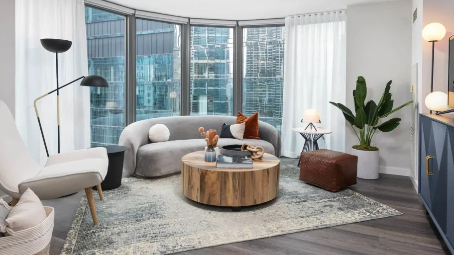 Modern living room at Shoreham and Tides apartments in Chicago featuring curved floor-to-ceiling windows, a round coffee table, and stylish seating