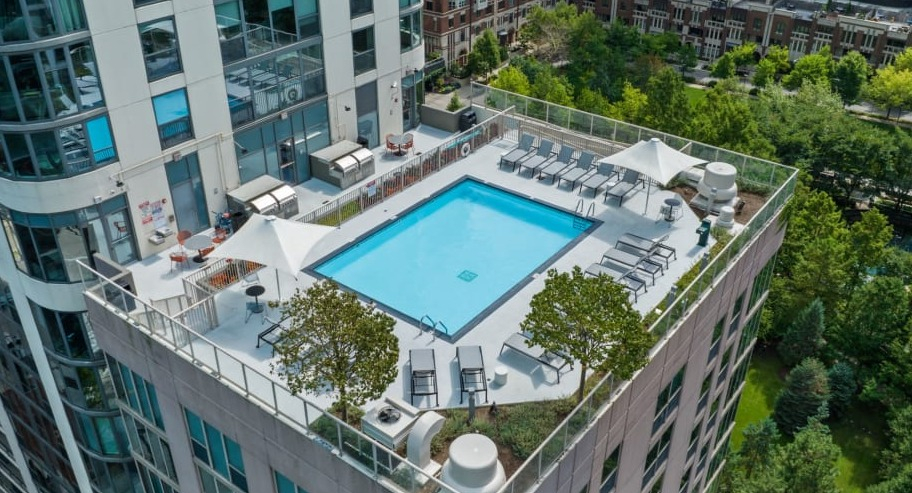 Rooftop pool and sun deck at Shoreham and Tides apartments in Chicago featuring lounge chairs, greenery, and scenic city and lake views