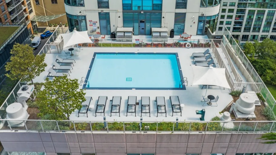 Aerial view of the rooftop pool at Shoreham and Tides in Chicago with rows of loungers, shade sails, and a secure perimeter terrace