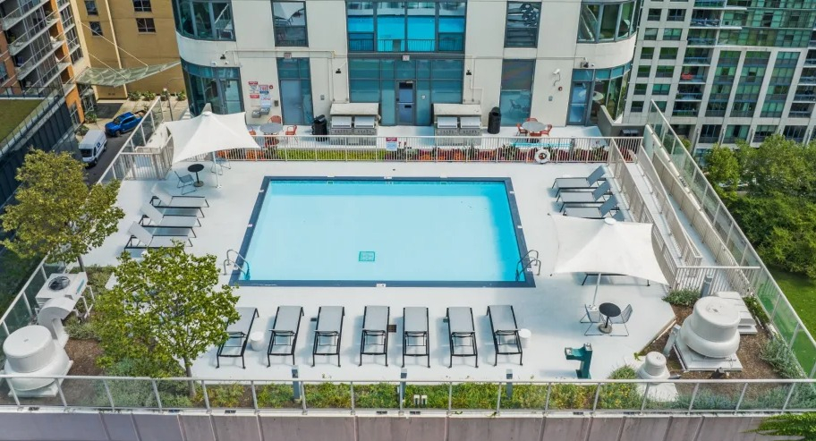 Aerial view of the rooftop pool at Shoreham and Tides in Chicago with rows of loungers, shade sails, and a secure perimeter terrace