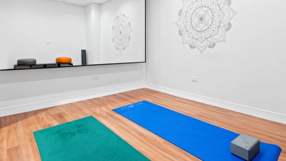 Minimal yoga and stretch studio at Shoreham and Tides in Chicago with wall mirror, mats, and wood-style floors for calm wellness sessions