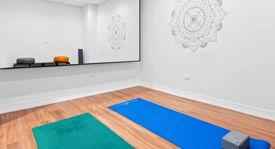 Minimal yoga and stretch studio at Shoreham and Tides in Chicago with wall mirror, mats, and wood-style floors for calm wellness sessions