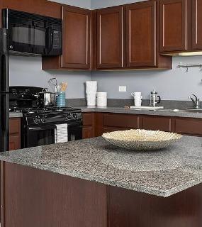 Kitchen with dark wood cabinets and granite countertops at Shoreham and Tides apartments in Chicago