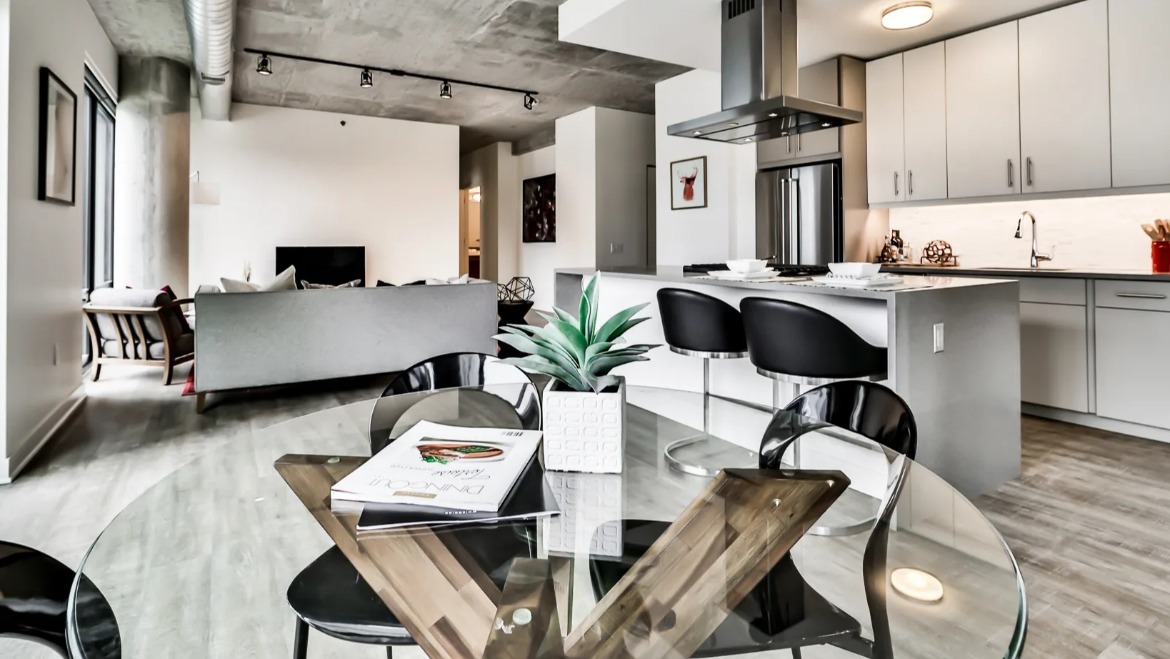 Open and bright dining, living, and kitchen area at Sienna in Chicago, featuring a glass dining table, comfortable seating, and a modern kitchen