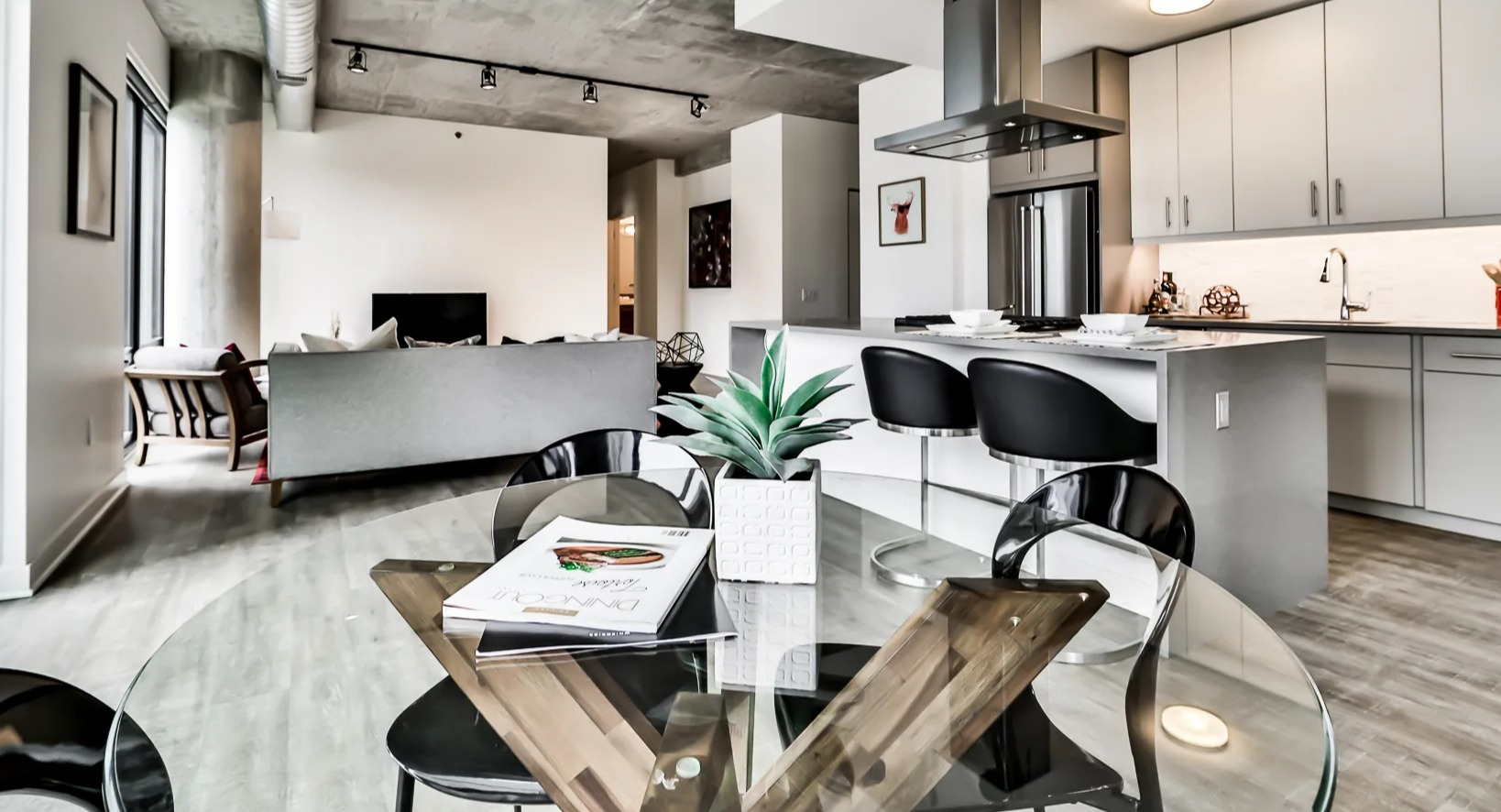 Open and bright dining, living, and kitchen area at Sienna in Chicago, featuring a glass dining table, comfortable seating, and a modern kitchen
