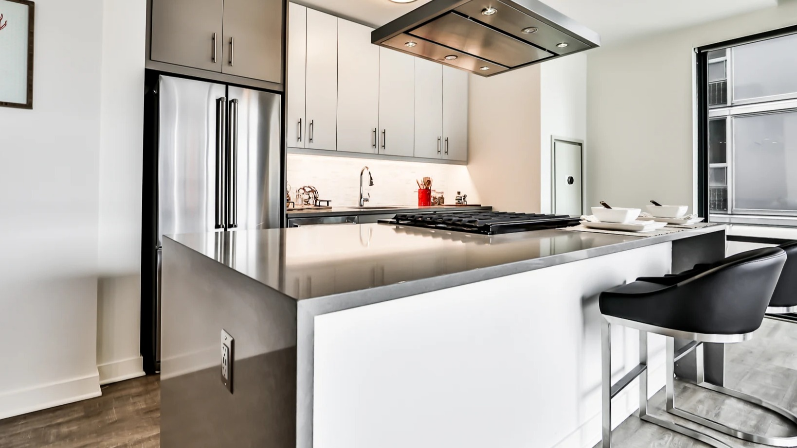 Sleek apartment kitchen at Sienna in Chicago, featuring a large island with bar seating, stainless steel appliances, and a modern range hood