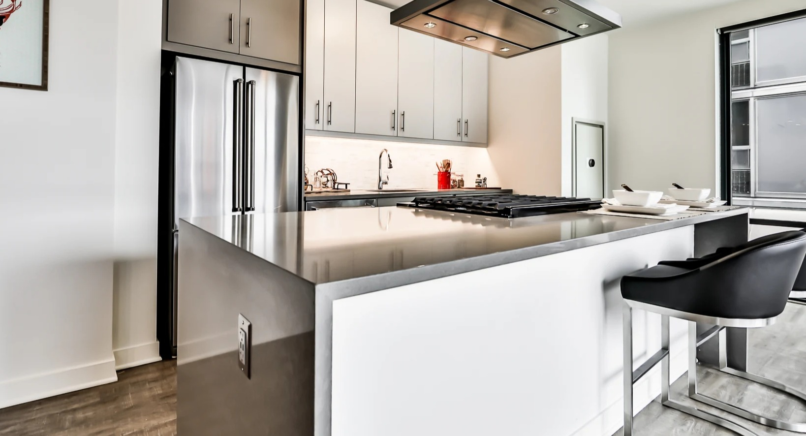Sleek apartment kitchen at Sienna in Chicago, featuring a large island with bar seating, stainless steel appliances, and a modern range hood