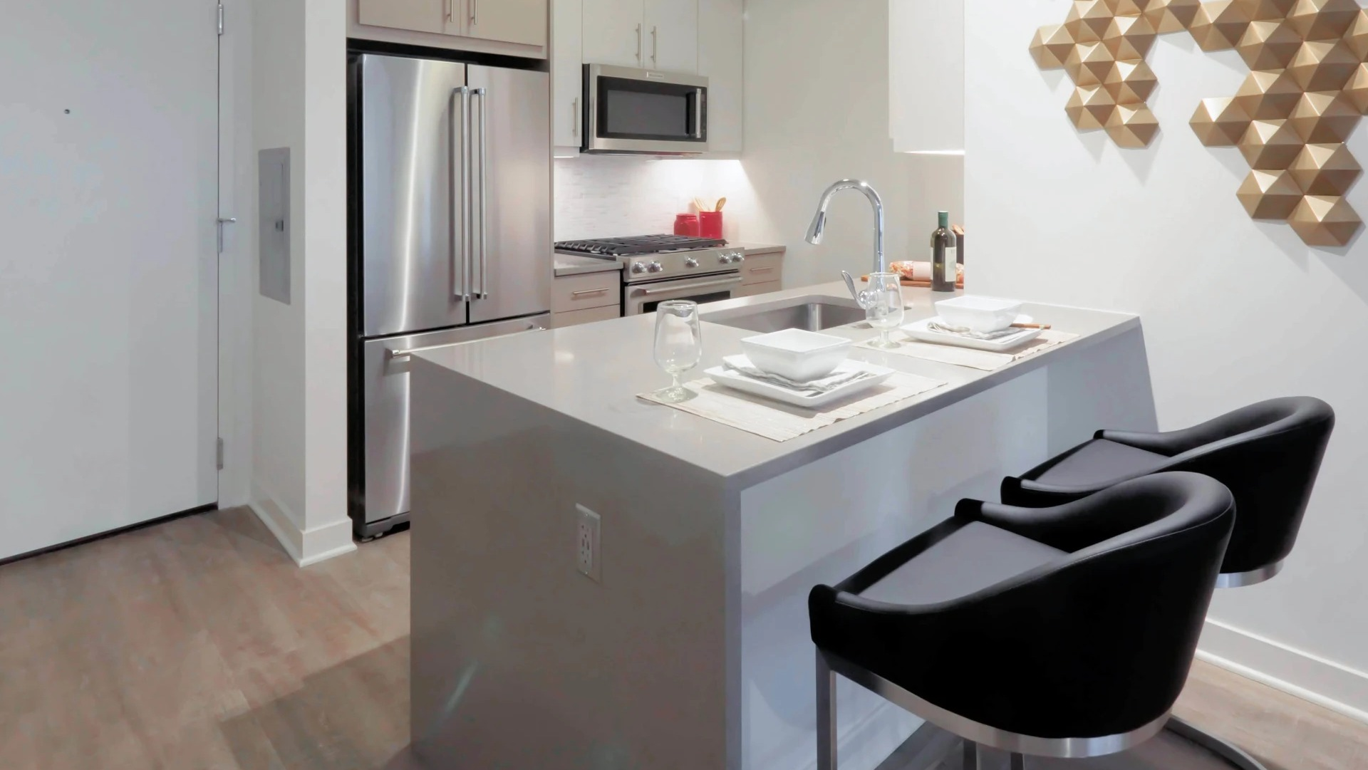 Modern apartment kitchen at Sienna in Chicago, featuring stainless steel appliances, light wood cabinets, and a kitchen island with seating