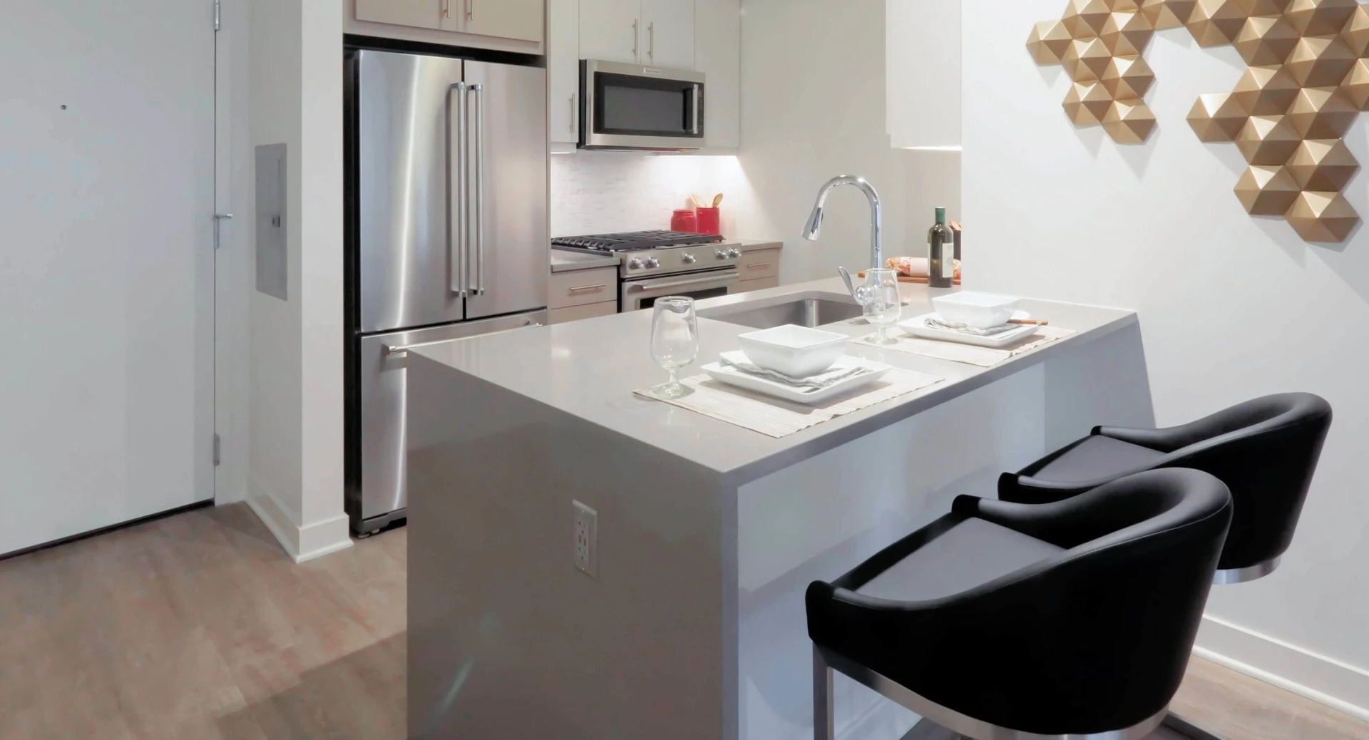Modern apartment kitchen at Sienna in Chicago, featuring stainless steel appliances, light wood cabinets, and a kitchen island with seating