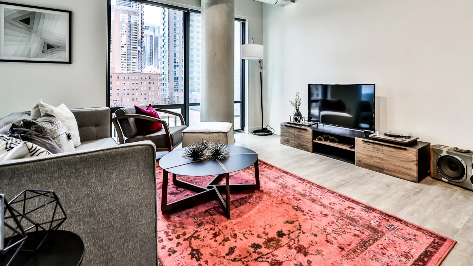 Contemporary living room at Sienna in Chicago, featuring a comfortable sofa, stylish rug, and expansive windows with urban views