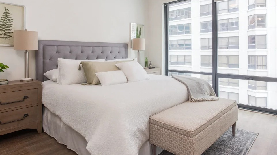 Spacious master bedroom at Sienna in Chicago, featuring a large bed, stylish nightstands, and expansive windows with city views