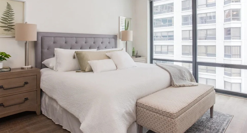 Spacious master bedroom at Sienna in Chicago, featuring a large bed, stylish nightstands, and expansive windows with city views