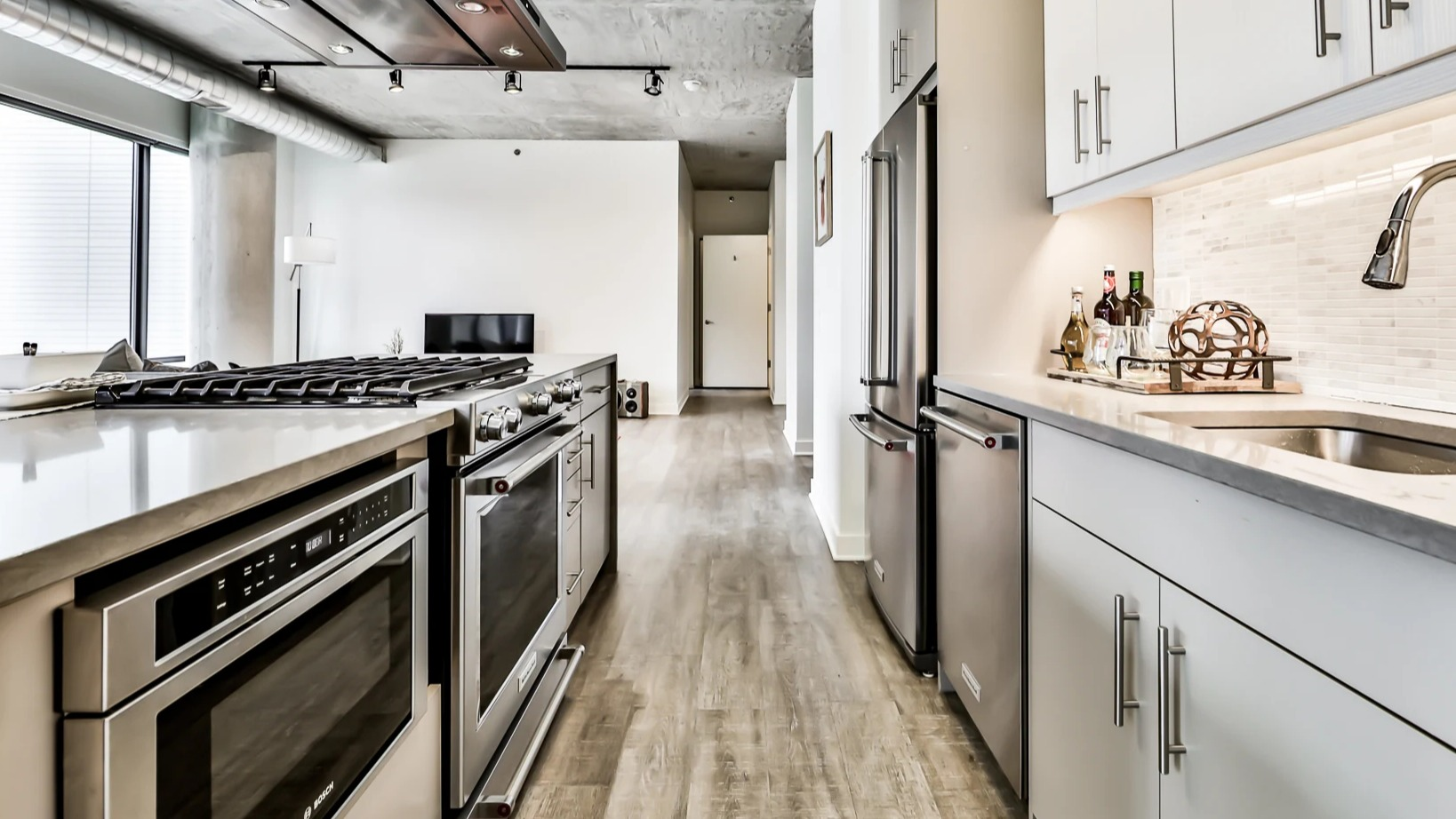 Modern open-concept kitchen and living room at Sienna in Chicago, featuring white cabinetry, stainless steel appliances, and sleek design