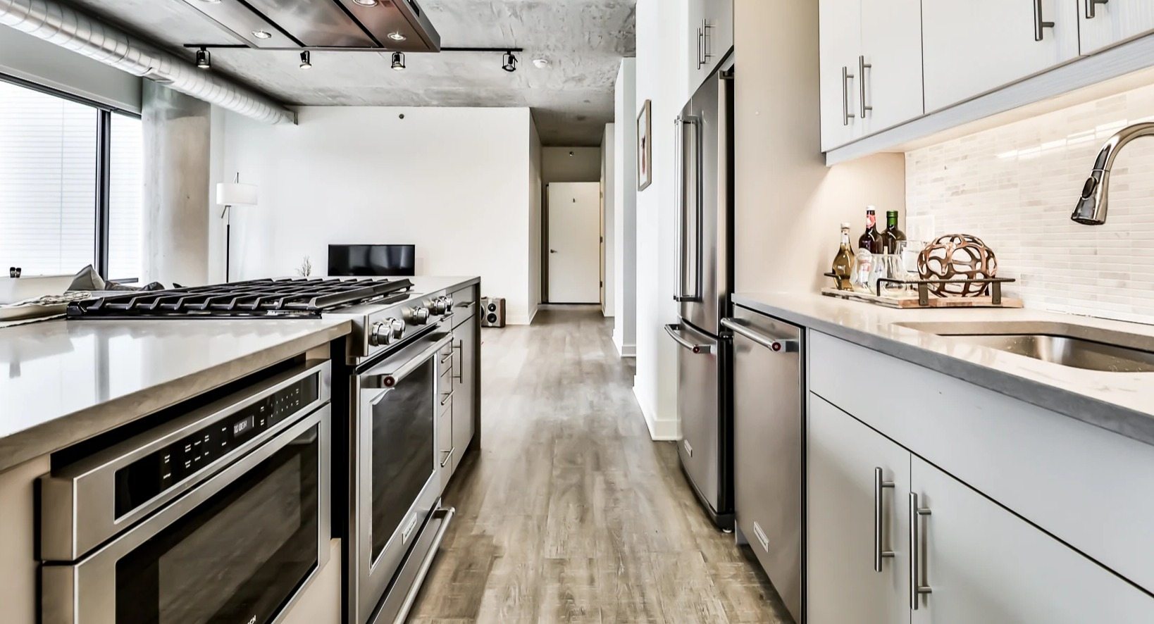 Modern open-concept kitchen and living room at Sienna in Chicago, featuring white cabinetry, stainless steel appliances, and sleek design