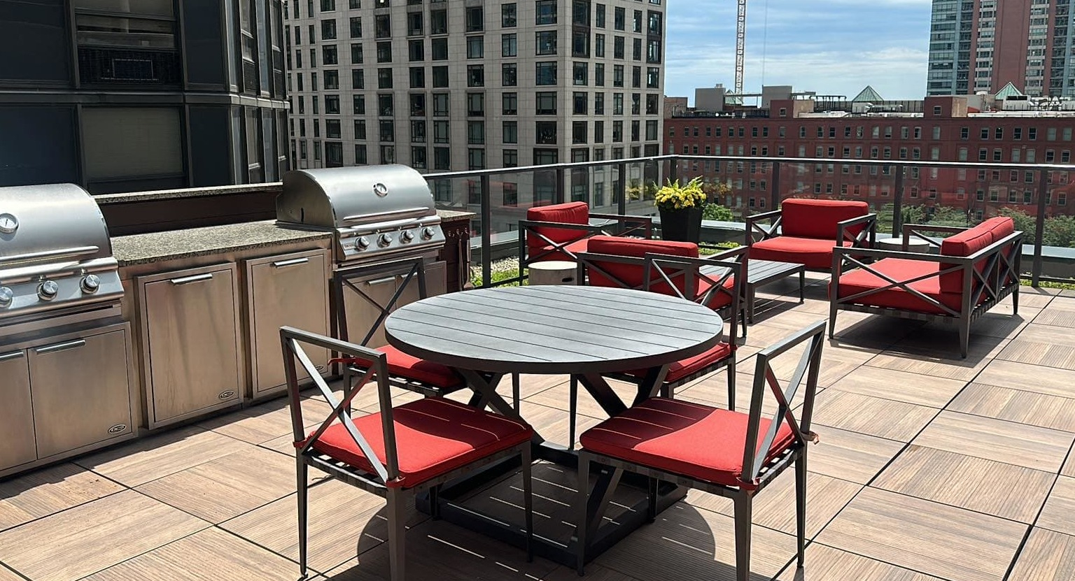 Inviting rooftop amenity deck at Sienna in Chicago, featuring grilling stations, an outdoor dining table, and comfortable lounge seating