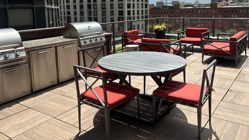 Spacious rooftop deck at Sienna in Chicago, featuring stainless steel grills, outdoor dining, and comfortable lounge furniture with city views