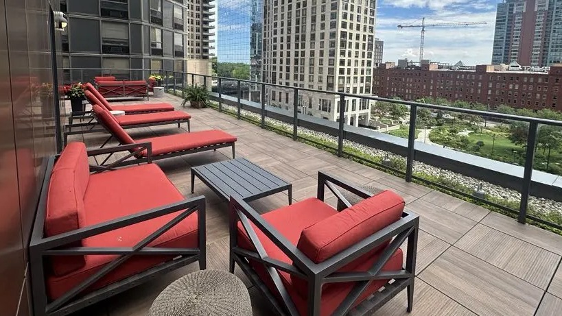 Scenic rooftop lounge at Sienna in Chicago, featuring comfortable red seating, lounge chairs, and stunning views of the city skyline
