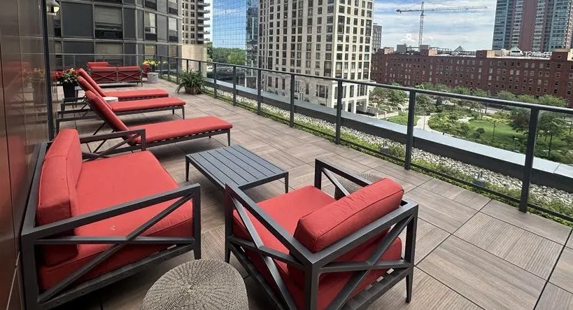 Scenic rooftop lounge at Sienna in Chicago, featuring comfortable red seating, lounge chairs, and stunning views of the city skyline
