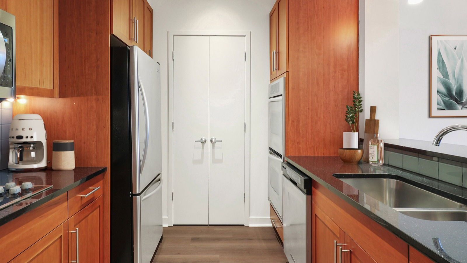 Efficient galley kitchen at SKY55 in Chicago, featuring warm wood cabinetry, stainless steel appliances, and ample counter space