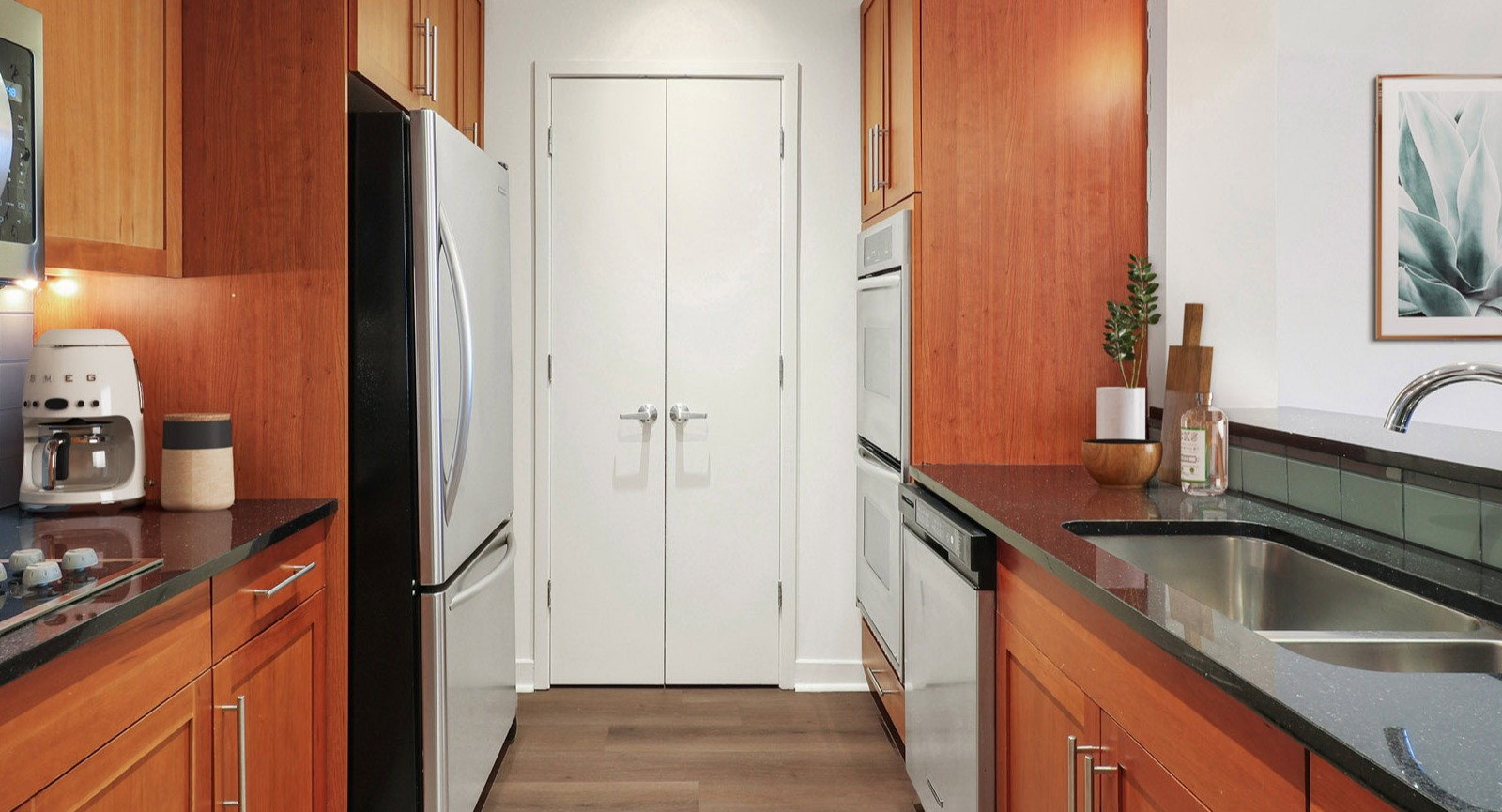 Efficient galley kitchen at SKY55 in Chicago, featuring warm wood cabinetry, stainless steel appliances, and ample counter space