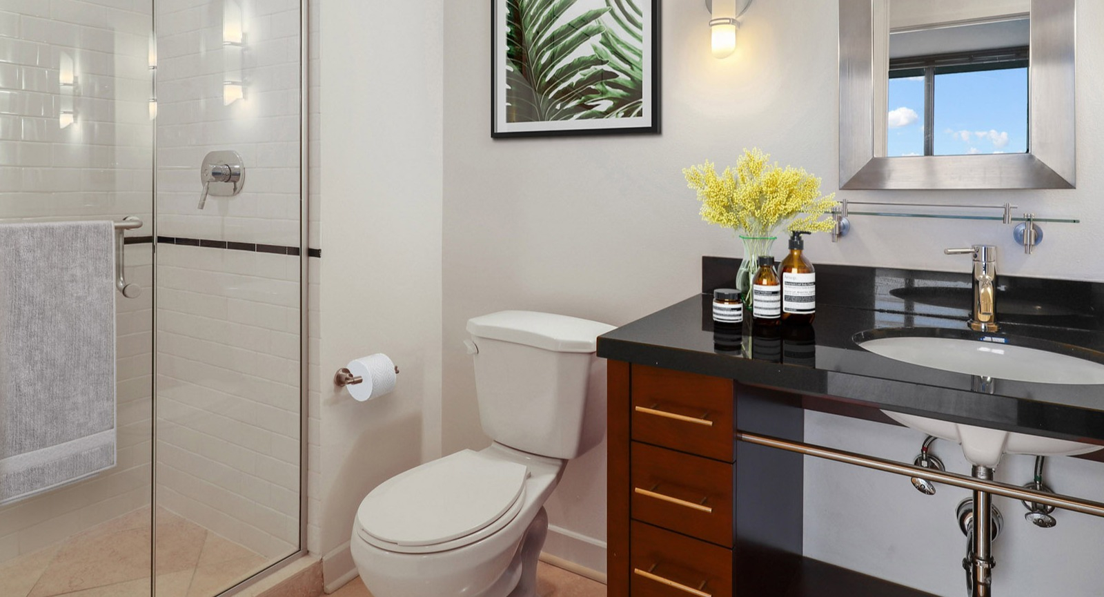 Modern guest bathroom at SKY55 in Chicago, featuring a sleek vanity, walk-in shower with white subway tiles, and contemporary fixtures