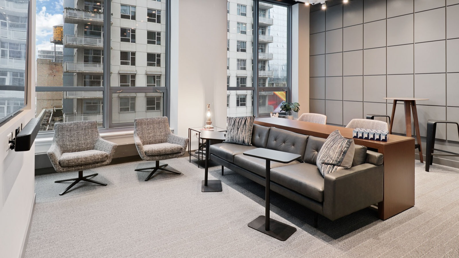 Modern resident lounge doubling as a co-working space with a large sofa, individual chairs, and ample natural light at SKY55 apartments in Chicago