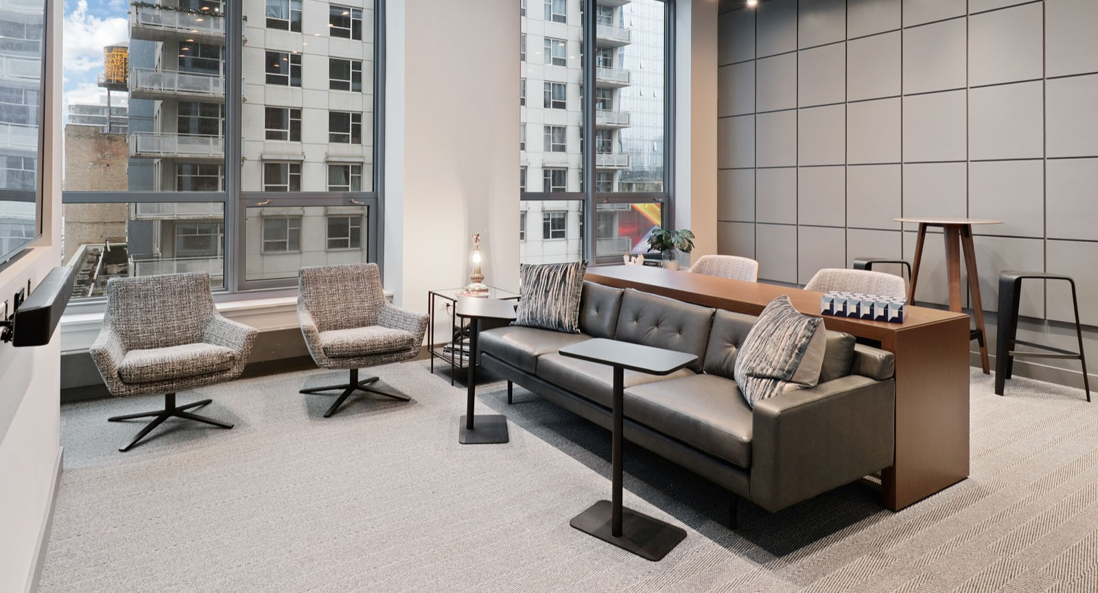 Modern resident lounge doubling as a co-working space with a large sofa, individual chairs, and ample natural light at SKY55 apartments in Chicago