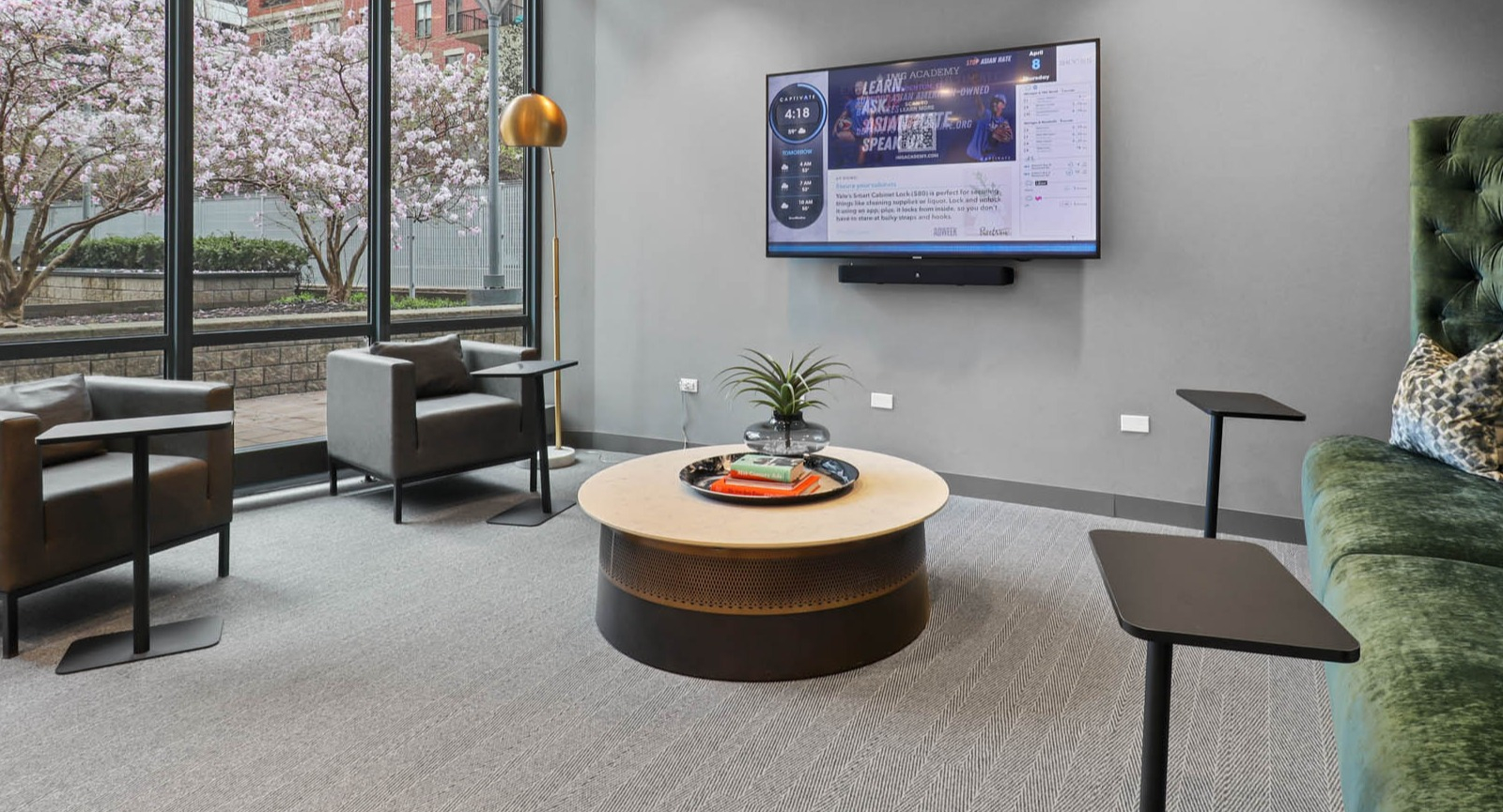 Cozy resident lounge with a plush green sofa, armchairs, and views of a lush outdoor garden area at SKY55 apartments in Chicago