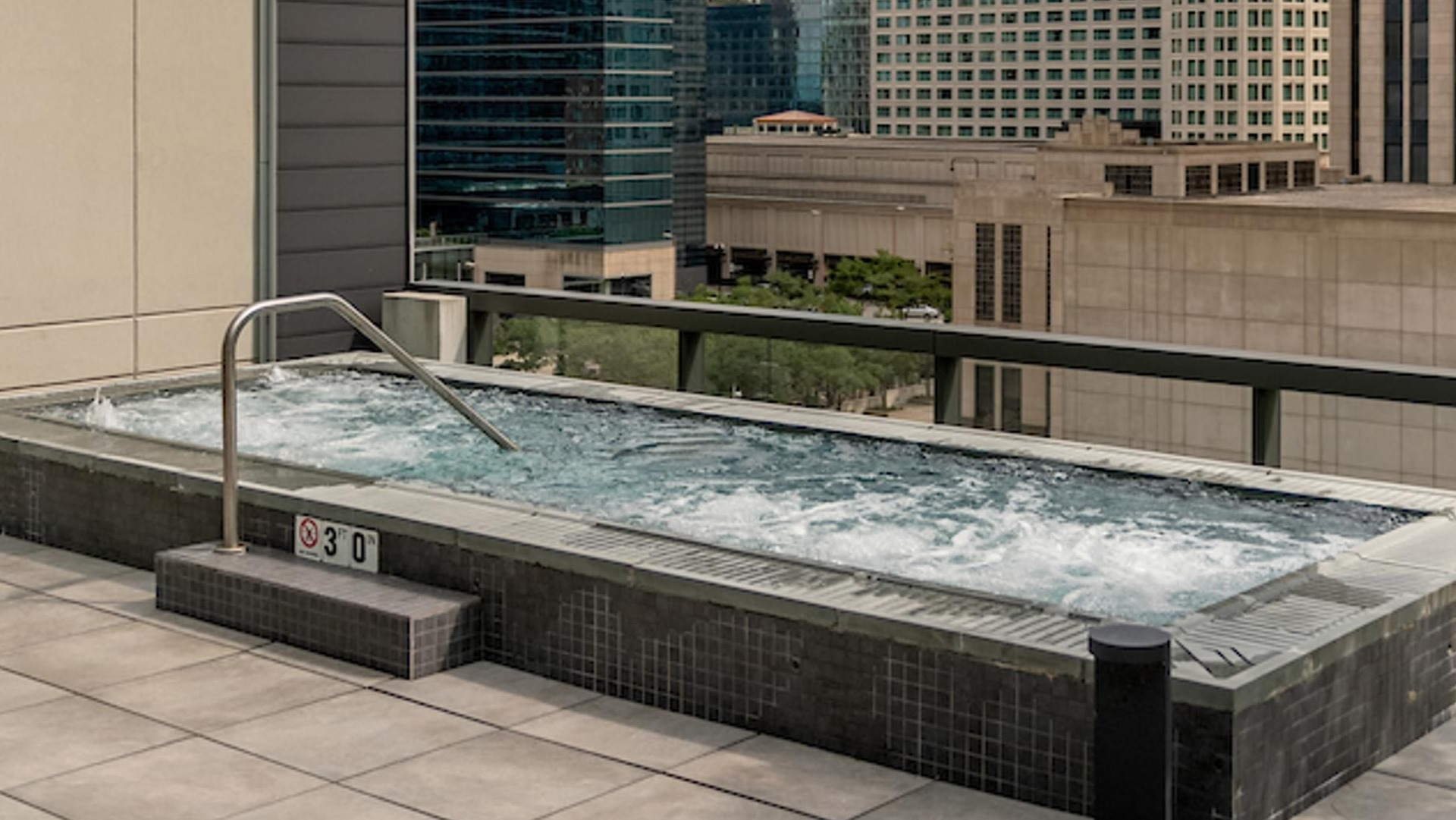 Rooftop hot tub terrace with bubbling water and dramatic downtown skyline views at Optima Signature apartments in Chicago