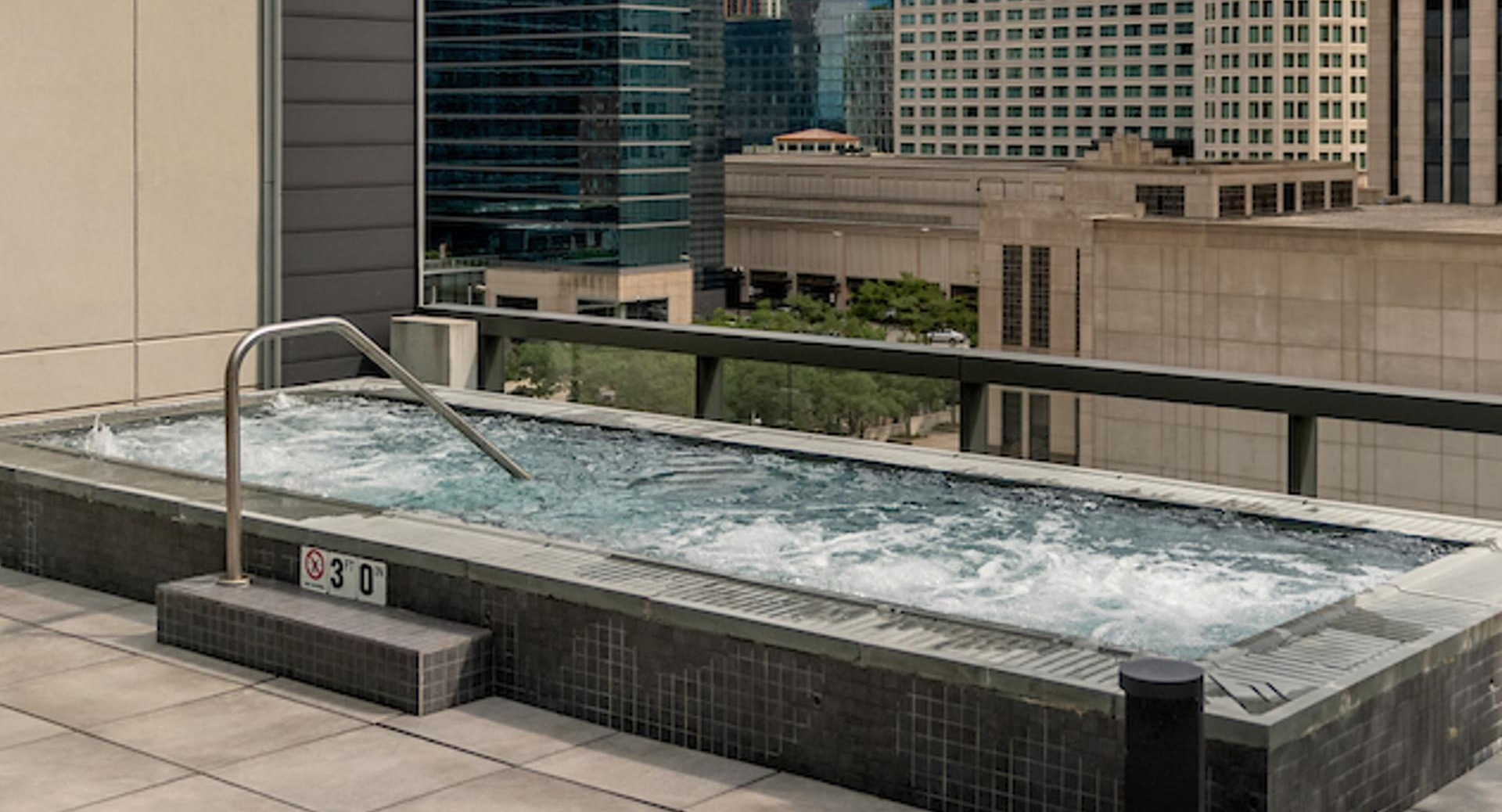 Rooftop hot tub terrace with bubbling water and dramatic downtown skyline views at Optima Signature apartments in Chicago