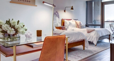 A cozy bedroom at SoNo East Apartments in Chicago, featuring a comfortable bed and a functional desk area for productivity