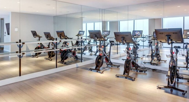 A well-equipped fitness center at SoNo East Apartments in Chicago, offering multiple spin bikes and mirrored walls