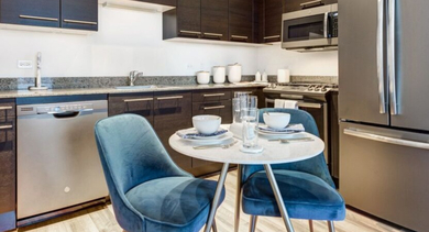 A sleek kitchen and dining area at SoNo East Apartments in Chicago, with modern appliances and stylish seating
